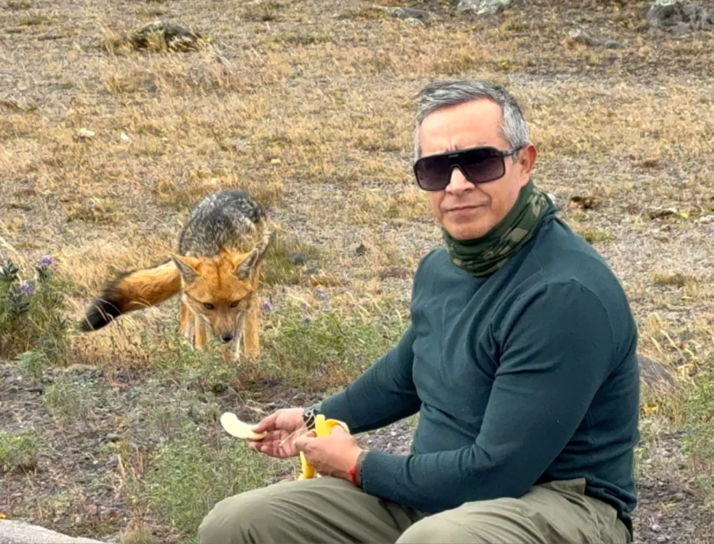 Ángel David Gavilanes al aire libre con un zorro andino al fondo; retrato natural.